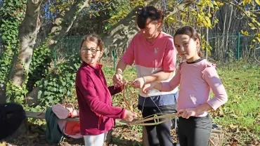 Une animatrice et deux enfants fabriquent des yoyos avec de la canne de Provence